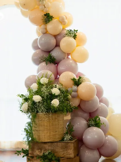 A detailed shot of the balloon arch and fresh floral arrangement in a wicker basket. This combination of elements added a rustic yet elegant touch to the baby shower decor.