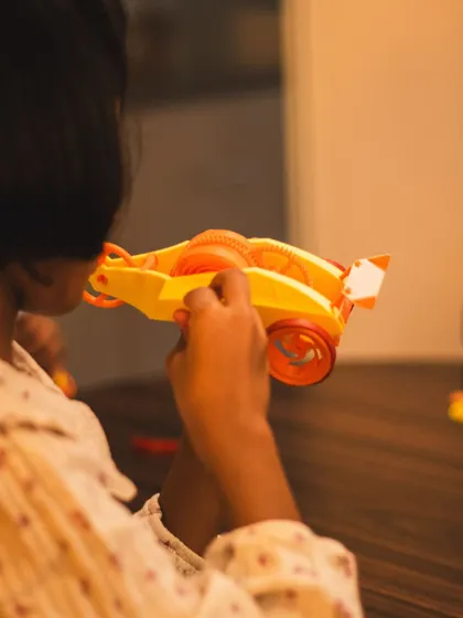 A student examines a 3D printed wind-up car. This project focuses on pure mechanics, using a spring and gears to power the vehicle without any electronics.