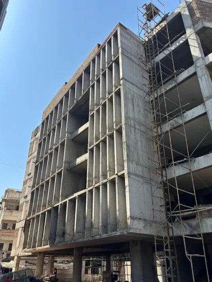 **Knowledge in Nooks, Ahmedabad:** The concrete shell of an urban community reading space. The facade's deep-set windows and varied openings hint at the quiet, focused nooks for reading that will be created within.