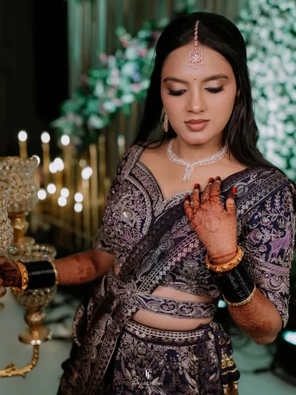 The bride looking serene and beautiful in her reception lehenga, with candles and ornate decor in the background.