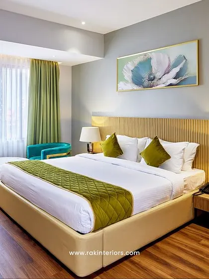A bright and airy hotel room design that combines natural wood tones with refreshing green accents. The layout includes a comfortable bed, a dedicated work desk, and a small seating area, making it ideal for business travelers.