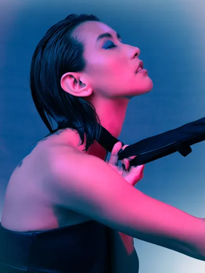 A beauty shot using dual-toned pink and blue lighting to create a vibrant, energetic mood. The wet-look hair and expressive pose add to the high-fashion feel.