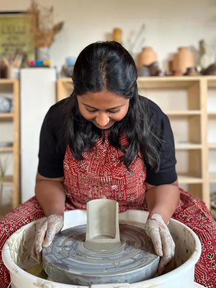 A professional course student proudly displays a cross section of her thrown cylinder, showing the even wall thickness she achieved through dedicated practice.