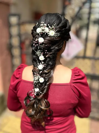 This is a messy mermaid braid, a popular choice for weddings and special events. I created this look by weaving together different sections and incorporating delicate baby's breath and white flowers for a romantic touch. It's an intricate style that looks both elegant and effortless.