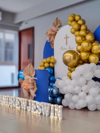 A modern Baptism decor setup in royal blue, white, and gold. The illuminated name and dried palm leaves add a contemporary and stylish touch.