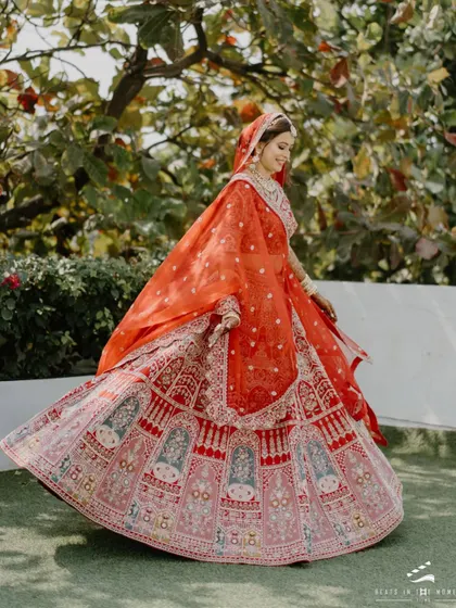 A bride twirls in her vibrant red lehenga, full of life and joy. This shot captures the beautiful movement of her outfit and her radiant happiness.