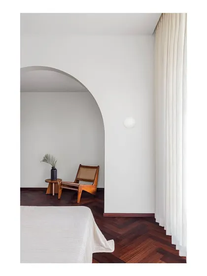 A master bedroom designed as a minimalist refuge. The simple archway creates a gentle transition into a quiet reading nook, demonstrating my belief that homes should provide spaces for peace and silence away from a frenetic world.