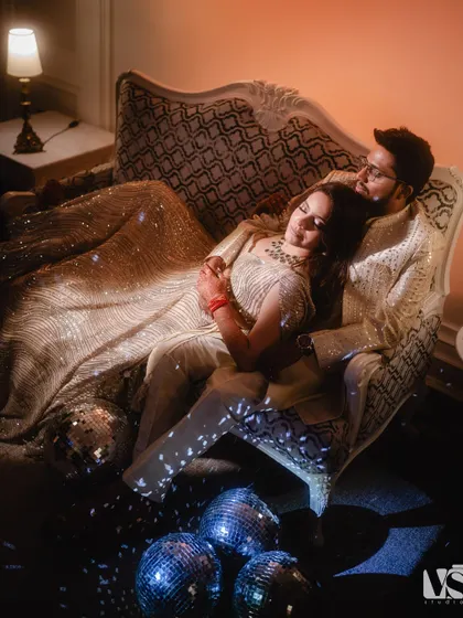 Another angle of the couple on the vintage sofa, this time from above. This perspective gives a sense of intimacy and quiet amidst the party atmosphere.