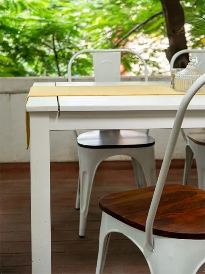 A close-up of the industrial-style dining chairs with solid wood seats. The combination of metal and wood offers a popular aesthetic that is both rustic and contemporary.
