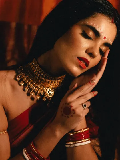 An intimate and artistic close-up of the model's face and hands. The image evokes a sense of quiet emotion and highlights the beautiful details of the bridal look.