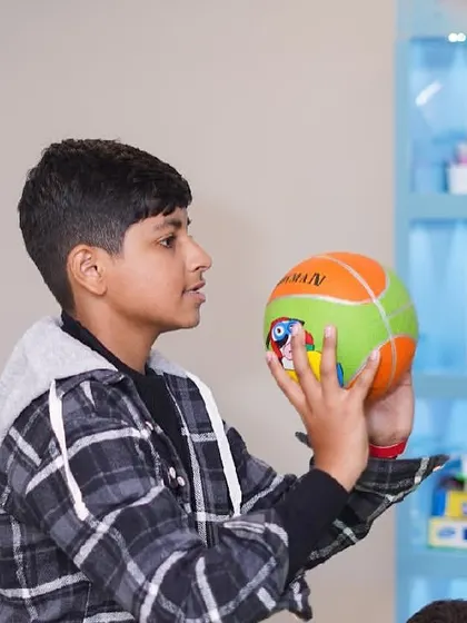 A boy examines a colorful ball during party games.