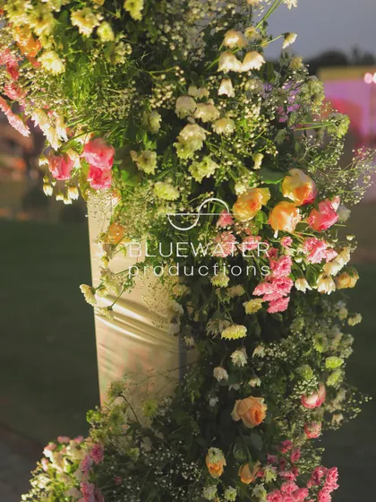 A detailed shot of a floral arrangement wrapped around a pillar, part of the elegant decor for the garden wedding.