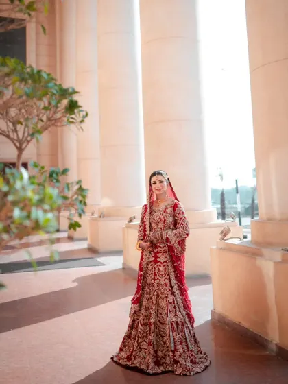 A full-length bridal portrait set against grand architectural pillars. The natural light and classic setting give this photo a timeless, elegant feel.