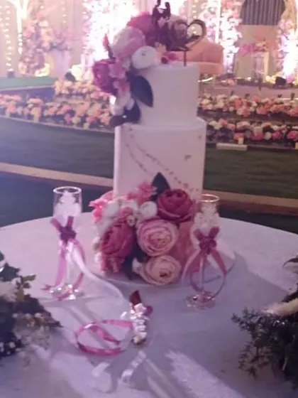 A beautifully decorated wedding cake table, with floral arrangements and personalized glassware.