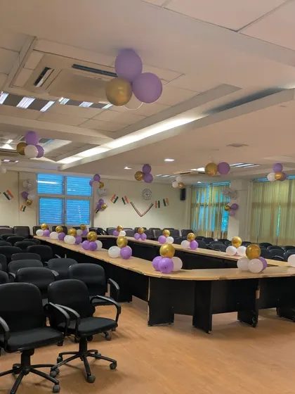 A view of the conference room decorated for the college event. Small balloon clusters on the tables and bunches on the ceiling fill the space with color.