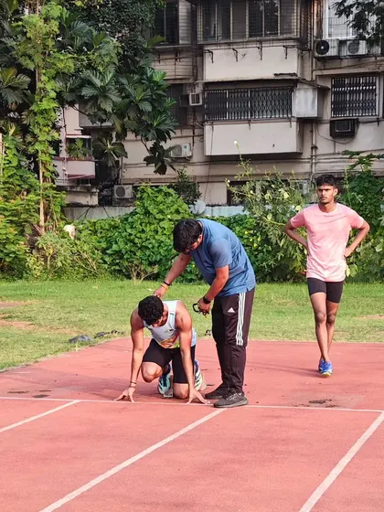 A normal day on the track, providing hands on correction for an athlete's starting position.
