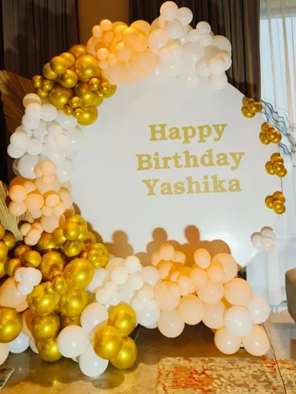 An elegant and clean design featuring a white circular backdrop personalized with "Happy Birthday Yashika". I framed it with an organic balloon garland in white, peach, and gold.