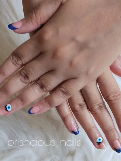 A different take on the evil eye trend, this time with winking eyes on the accent nails combined with a classic blue French tip.