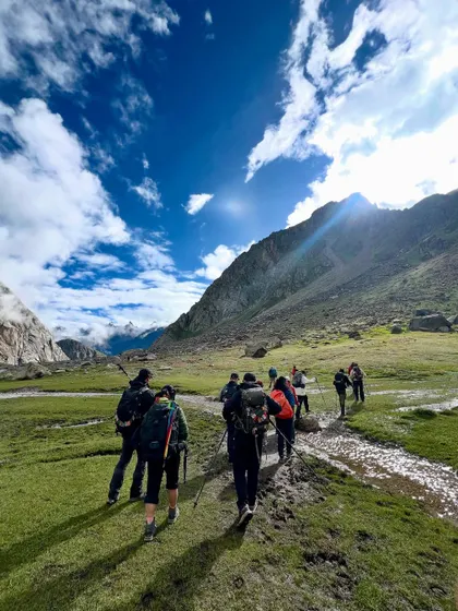 Walking through the vast meadows of the Hampta valley, with the trail stretching out ahead.