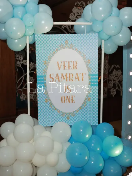 A simple yet elegant welcome sign for Veer Samrat's first birthday, framed by blue and white balloons that match the party's color scheme.