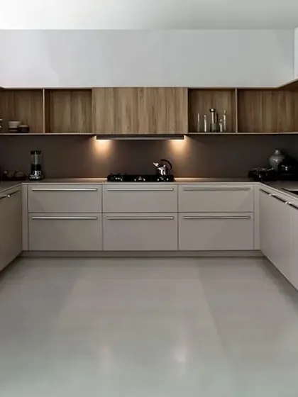 This minimalist kitchen features handle-less cabinets in a muted tone and wood-finish overhead units, achieving a sleek and modern aesthetic.