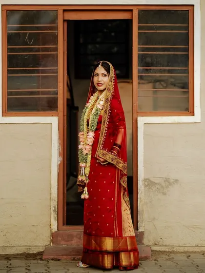 A full-length shot of the bride, framed by a doorway. Her traditional attire looks stunning.