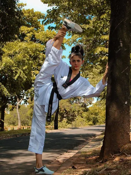 Using the environment to enhance training. A student uses a tree to deepen her stretch, demonstrating the creativity and dedication we encourage.