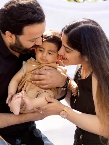 A tender moment as parents kiss their baby's cheeks. This close-up shot emphasizes the love and affection in the family.
