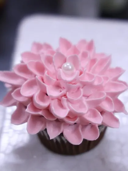 A close-up of a dahlia cupcake made with delicate pink frosting petals and a pearl center. This is one of the techniques I teach in my basic cupcake workshops.
