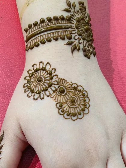 This is a beautiful example of a simple, modern design applied on the hand. It combines a delicate wristband with floral motifs, showing how beginner elements can create a professional and trendy look.
