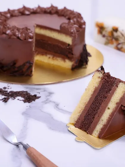 We offer a classic indulgence with our rich chocolate layer cake. Alternating layers of vanilla sponge and deep chocolate fudge frosting are covered in a smooth chocolate ganache, creating a simple yet profoundly satisfying dessert.