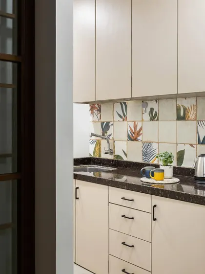 The office pantry is both stylish and functional. We used simple beige cabinets and a backsplash of playful, nature-inspired tiles to create a pleasant space for a coffee break.