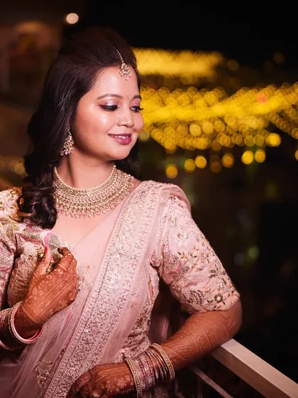 A beautiful shot of Kajol on her reception night. Her soft pink lehenga is paired with a glowing, romantic makeup look, perfect against the backdrop of city lights.