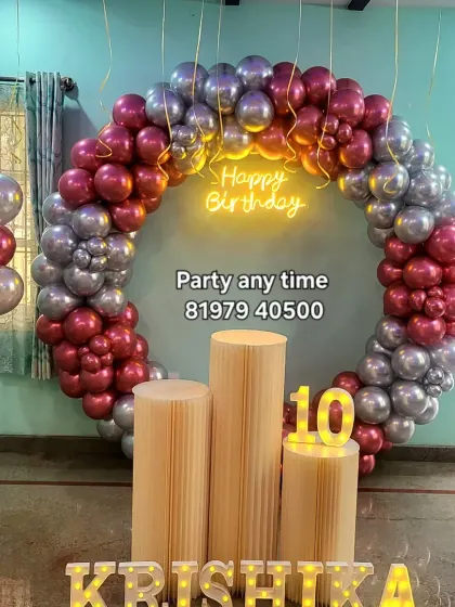 A beautiful 10th birthday setup with a circular balloon arch in chrome pink and silver, a neon sign, and light-up letters.