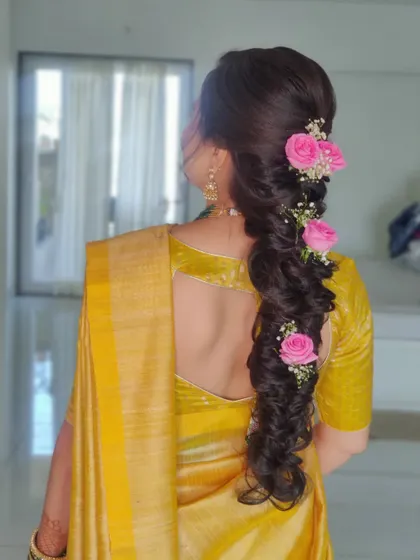 A detailed look at her messy fishtail braid adorned with fresh pink roses.