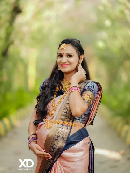 A beautiful close-up portrait of the mother-to-be, showcasing her pregnancy glow and the intricate details of her traditional jewelry and saree.