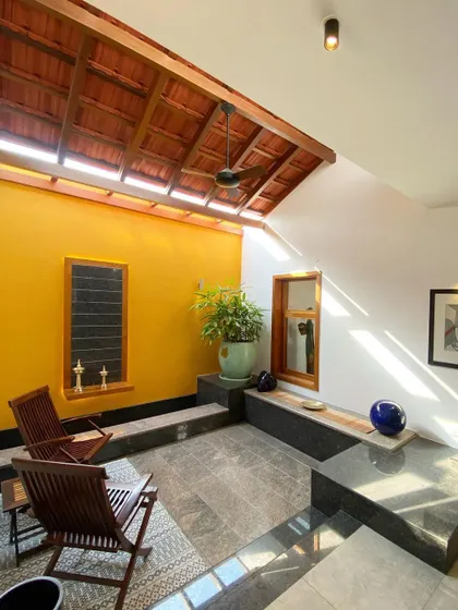 This semi-open seating area is illuminated by a long skylight set into the traditional tiled roof. The design allows for abundant natural light while protecting from the elements, creating a perfect transitional space.