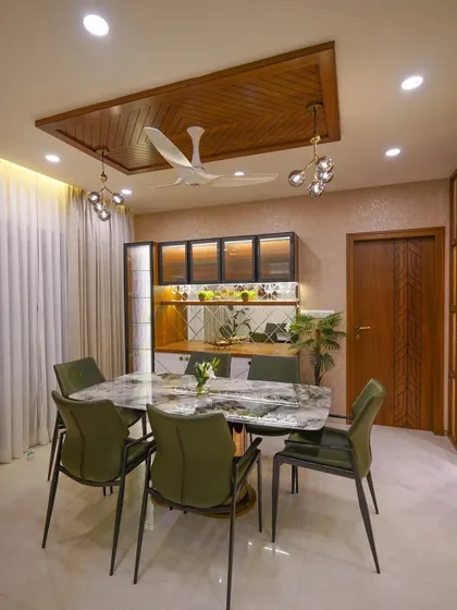An elegant dining space designed for family gatherings. The marble-topped table is paired with comfortable upholstered chairs, while a custom crockery unit with backlighting provides both storage and a beautiful display.