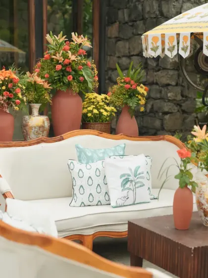 A comfortable and stylish lounge area for guests at a Haldi ceremony, with vintage-style sofas, printed cushions, and a block-printed umbrella.
