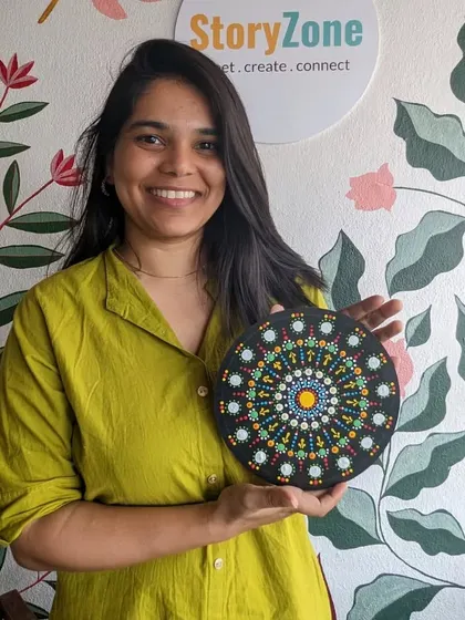 A participant proudly holding her finished dot mandala. The intricate patterns and bright colors make for a stunning piece of decor.