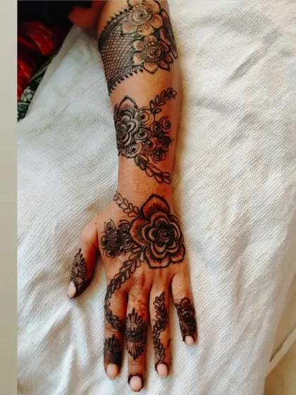This design combines a large floral motif on the back of the hand with a net pattern on the wrist cuff. It’s a great example of mixing different mehendi elements.