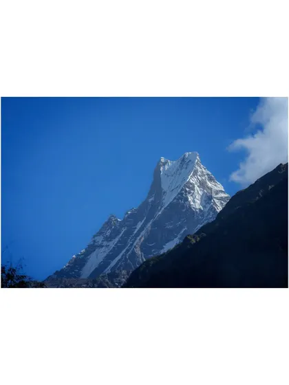 The sharp, snow-covered peak of Machapuchare against a brilliant blue sky. The clarity and majesty of the Himalayas are on full display here.