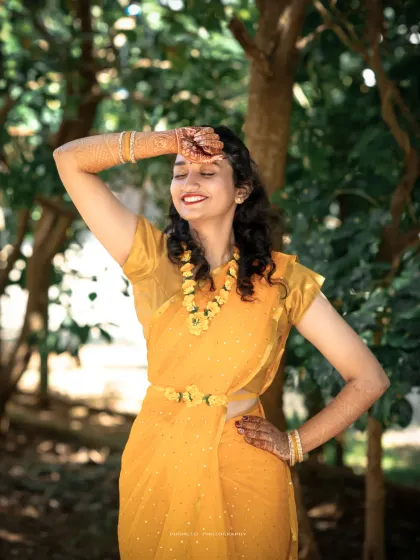 A radiant bride basking in the sun, her yellow saree and floral jewelry perfectly matching the Haldi theme.