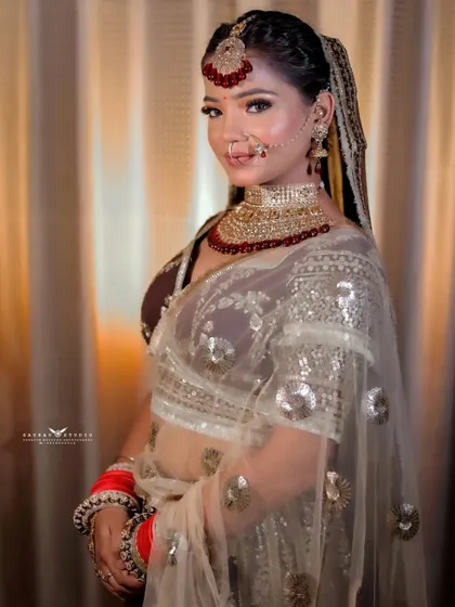 A three-quarter shot of the bride, with her sheer, sequined dupatta creating a beautiful, light-filled frame around her. Her confident expression completes the look.