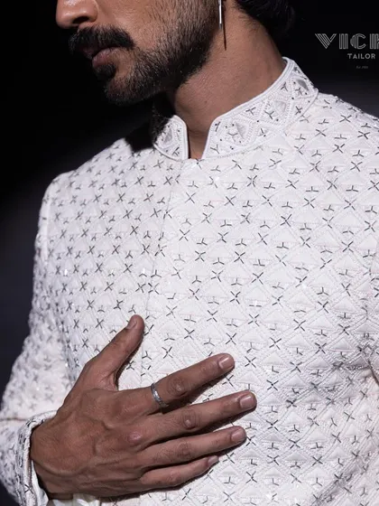 A close-up of the intricate geometric embroidery on one of our white sherwanis. This image highlights the precision and texture that define our craftsmanship.