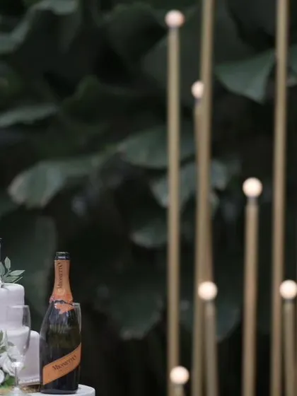 A beautiful wedding cake and champagne, set against a backdrop of modern light installations, ready for the celebration.