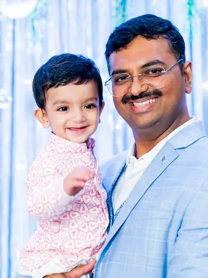 A happy father holding his one-year-old son. The smiles on both their faces are infectious, making this a heartwarming portrait from the birthday celebration.