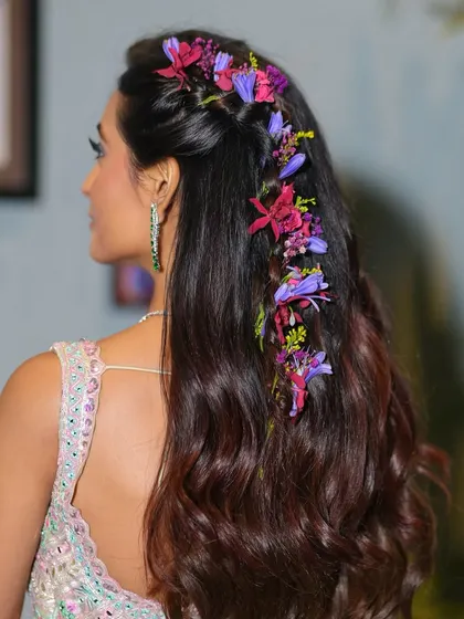 A detailed shot of the floral braid, a key element of this Mehendi look. The fresh flowers woven through her hair add a touch of natural, romantic beauty that complements the pastel outfit.