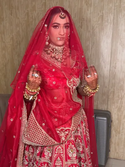 A playful moment with the veil. The sheer red fabric creates a beautiful filter, highlighting the flawless makeup and intricate jewelry underneath.