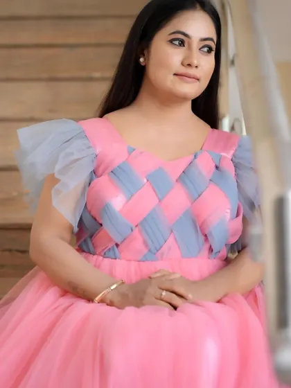 A seated portrait in the pink and grey ball gown, showing how the design looks elegant and poised. This gown is worn by celebrity Straight Hit Suguna.